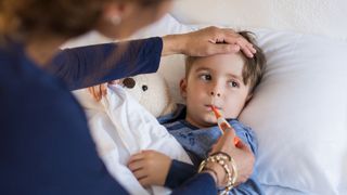 Mother taking her son's temperature using an oral thermometer