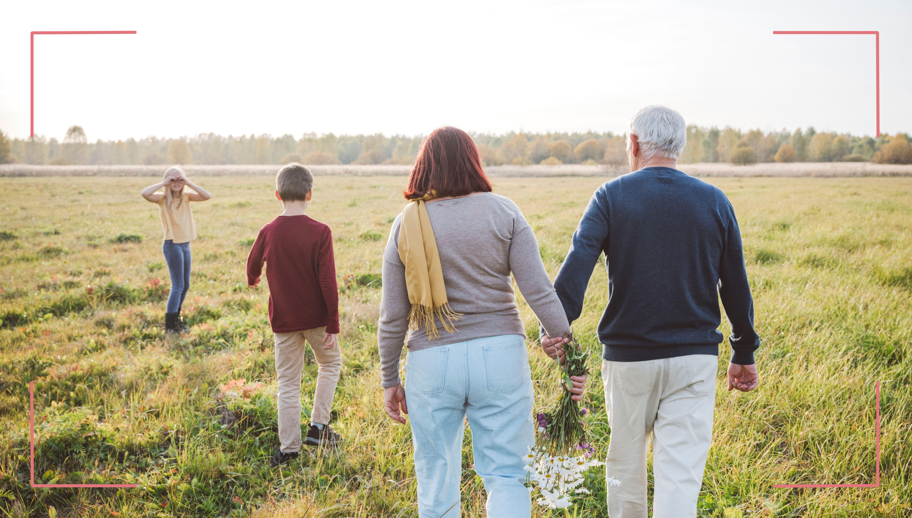 Grandparents walking through a field with their children