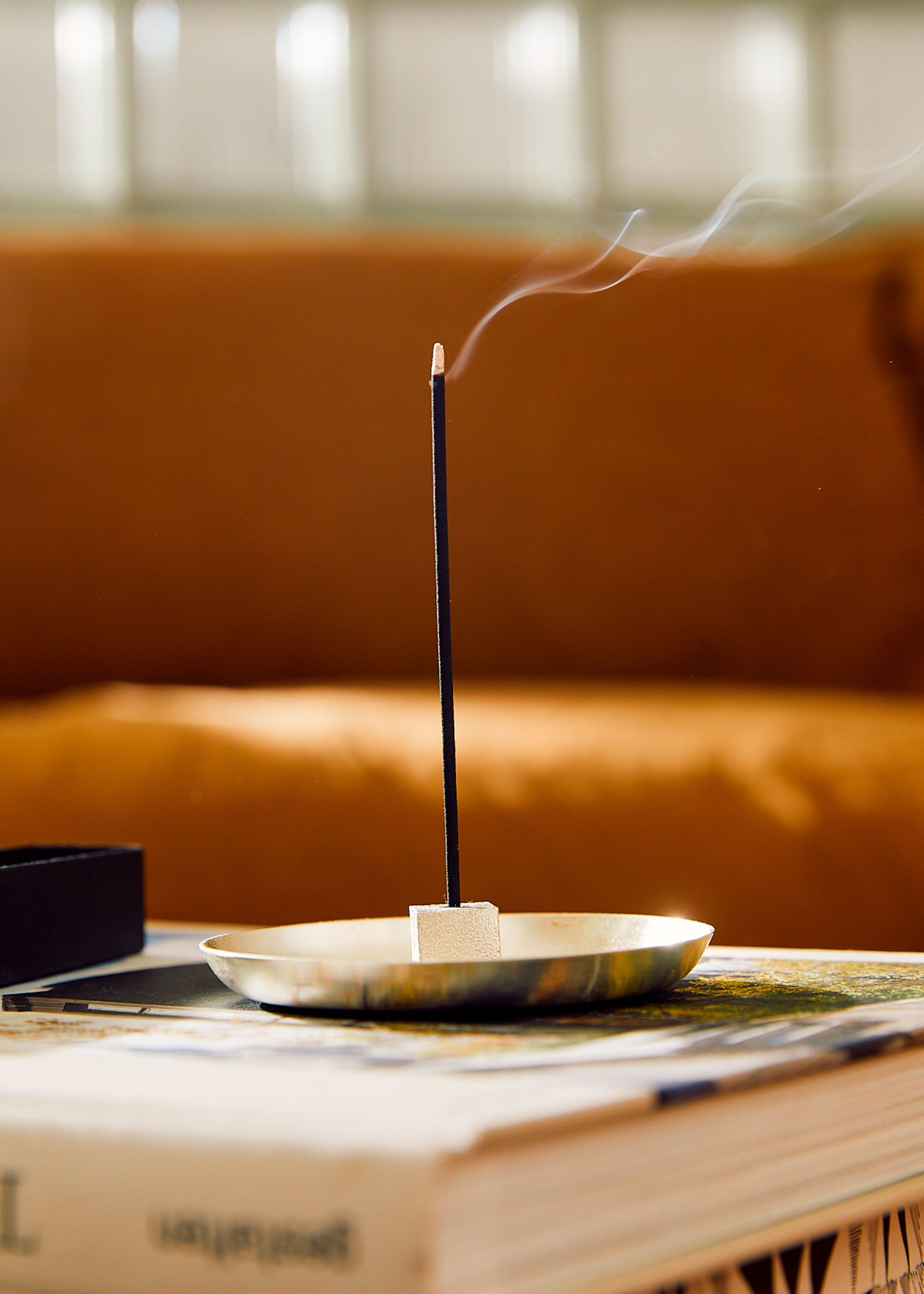 An incense stick from Earl of East burning in a cement holder on a coffee table