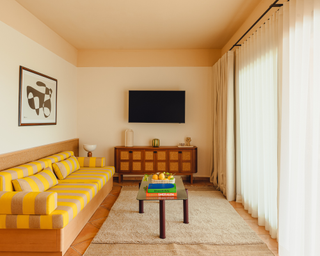 Yellow striped couch in neutral living room space with lemons on coffee table alongside colorful books