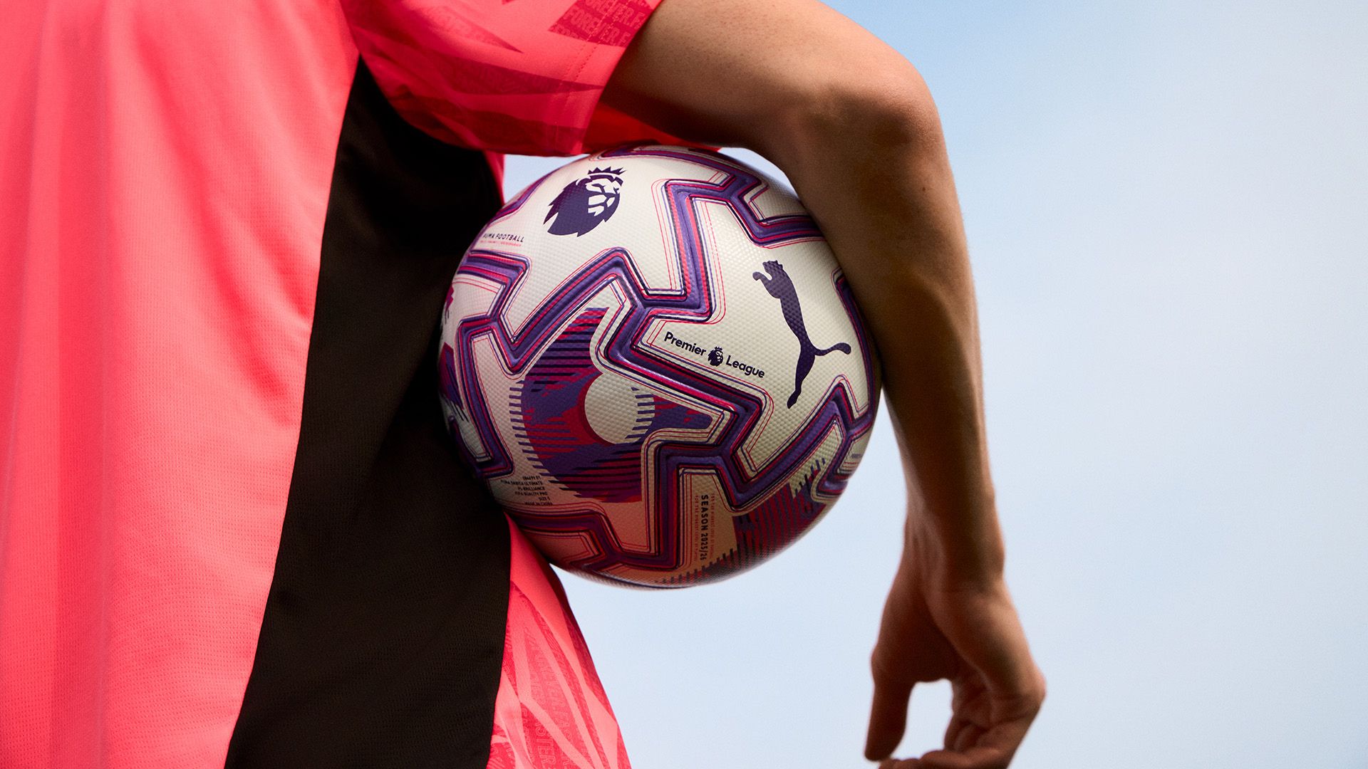 an image of the new PUMA x Premier League match ball carried under the arm of a player in a pink sport shirt