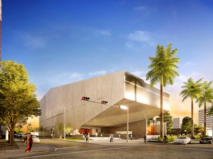 An exterior view of the grey concrete Berkowitz Contemporary Foundation building with palm trees iin front by the main road and people walking in and out of the building