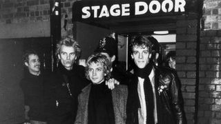 18th December 1979: The pop group Police outside the stage door of a Hammersmith venue in west London, with a policeman standing behind them. From left to right, they are Sting, Andy Summers and Stewart Copeland