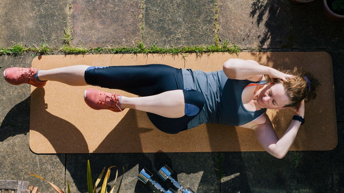 Woman performs bicycle crunch in garden