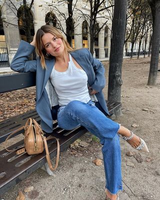 French woman wearing St. Agni white tank, jeans, and blue blazer.