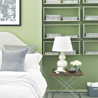 bedroom wall decor idea, green bedroom with box shelving in matching paint, white bedding, artwork, bedside with white lamp