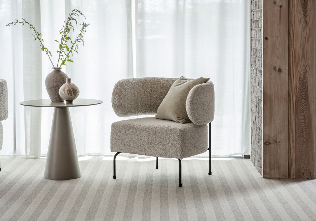 A mid-century modern armchair and side table on a neutral light beige carpet