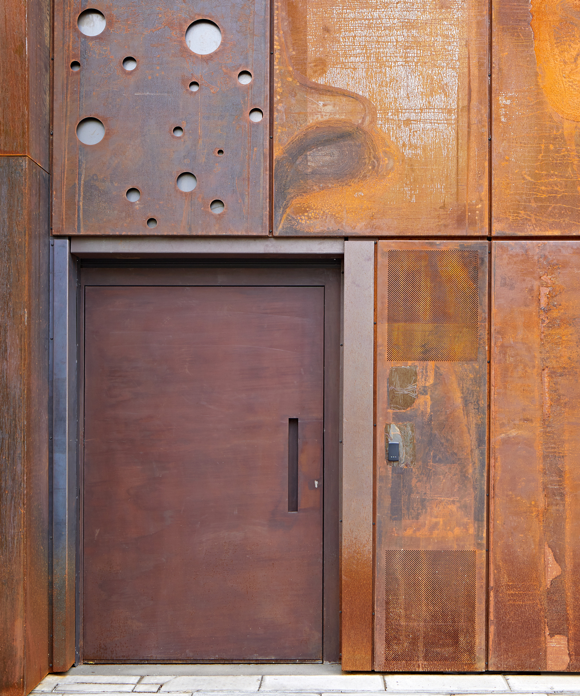 large corten steel front door on corten steel clad home