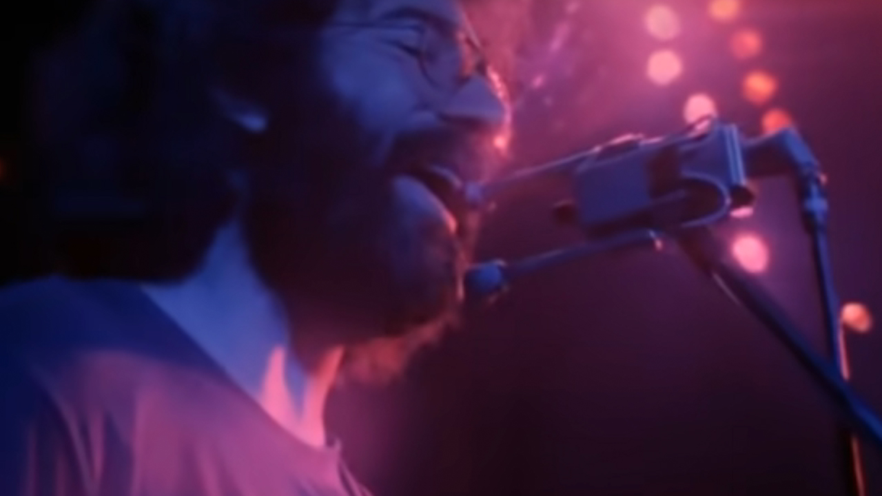 Close up of Jerry Garcia singing on stage with two microphones