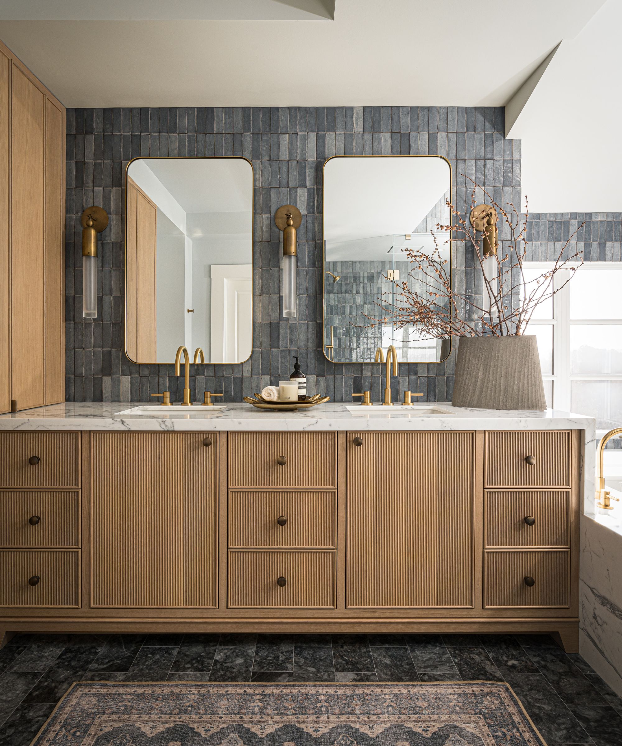 A moody bathroom with blue wall tiles and a wooden vanity