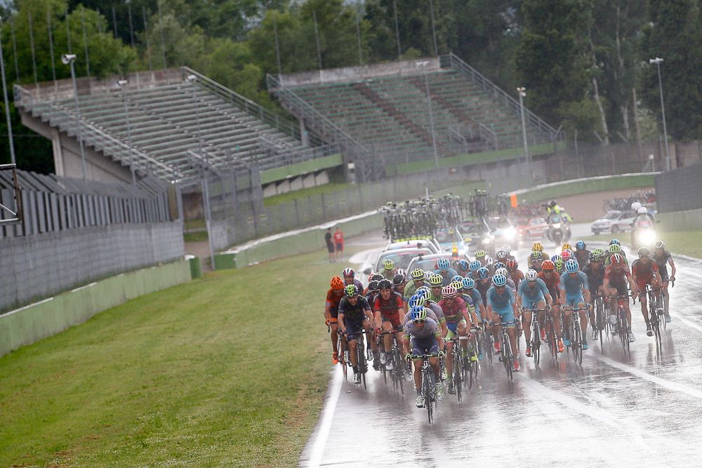 The peloton kicks up water from the surface of the F1 track in Imola.