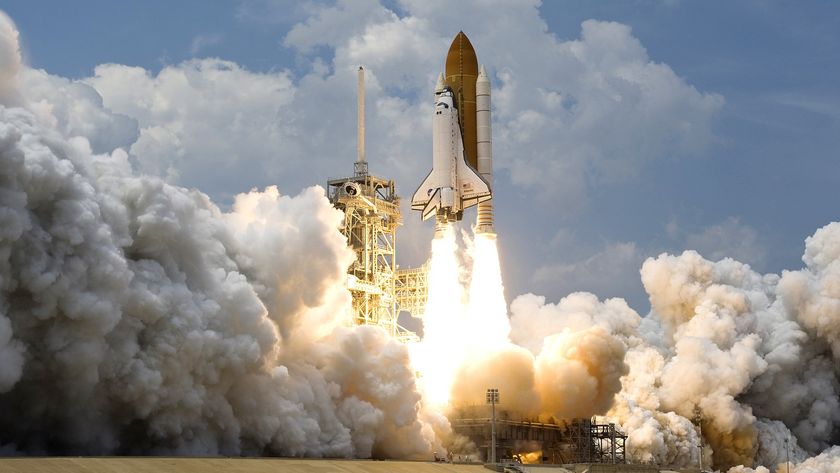 A white space shuttle launches off a pad with large clouds of smoke underneath it