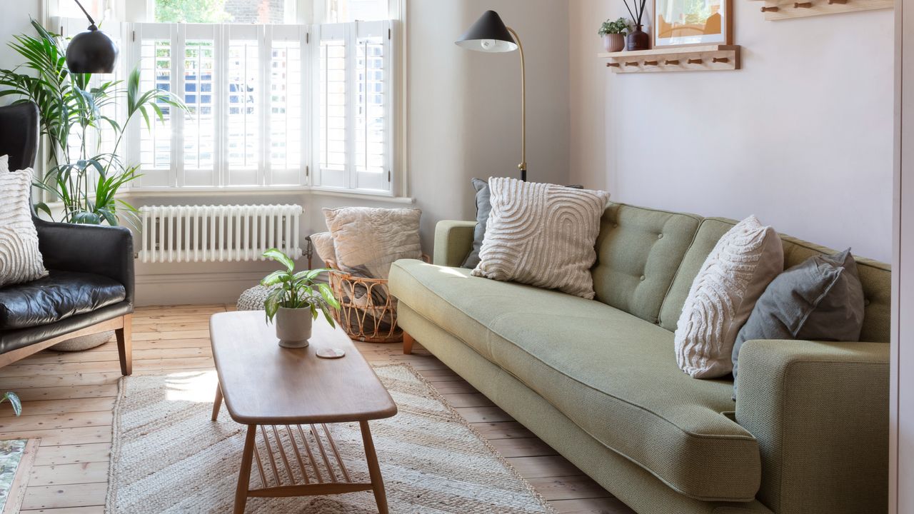 A living room with a green 3-seater sofa and a mid-century modern-style coffee table in front of it on a rug