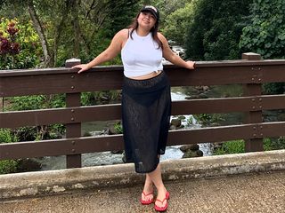 marina wears black bikini, sheer skirt, white tank top, and red flip flops.