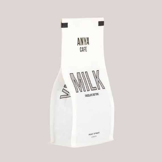 A black and white bag looking like a coffee beans bag reads "ANYA CAFE MILK" sits against a faint grey background.