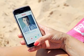 Woman on the beach using the dating app Tinder.