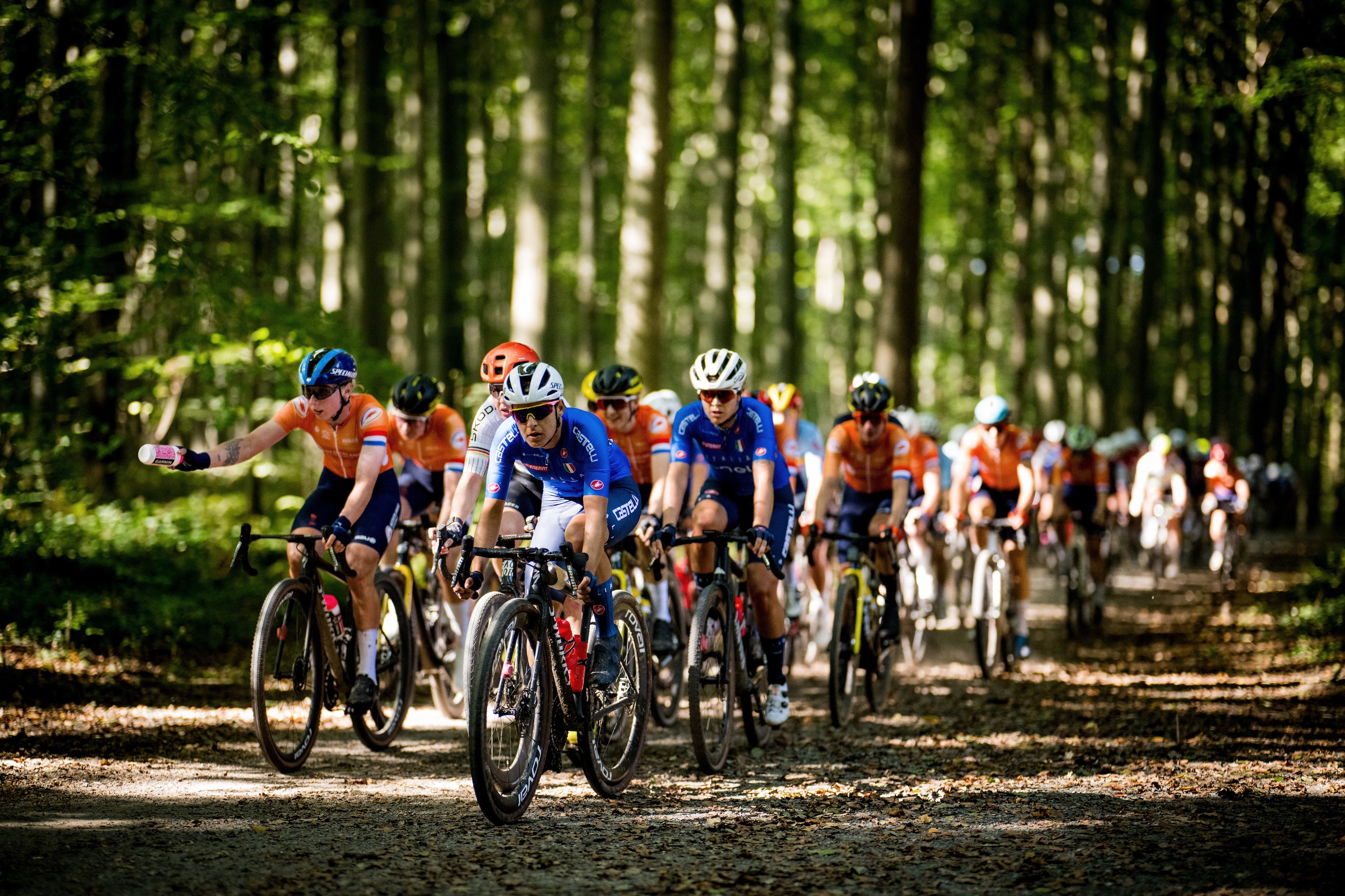 The elite women's peloton at the 2024 Gravel Worlds, led by Italy in blue and the Netherlands in orange