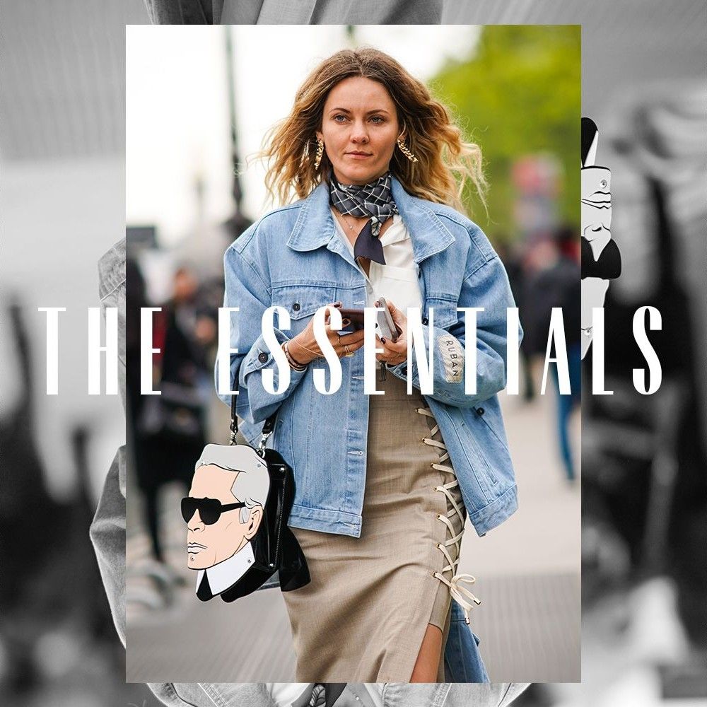 A woman walking down a street wearing a denim jacket. Text over the image reads "The Essentials"
