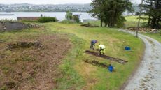 Here this photo shows an aerial view of two people digging on the burial ground (a grassy area free of trees or shrubs).