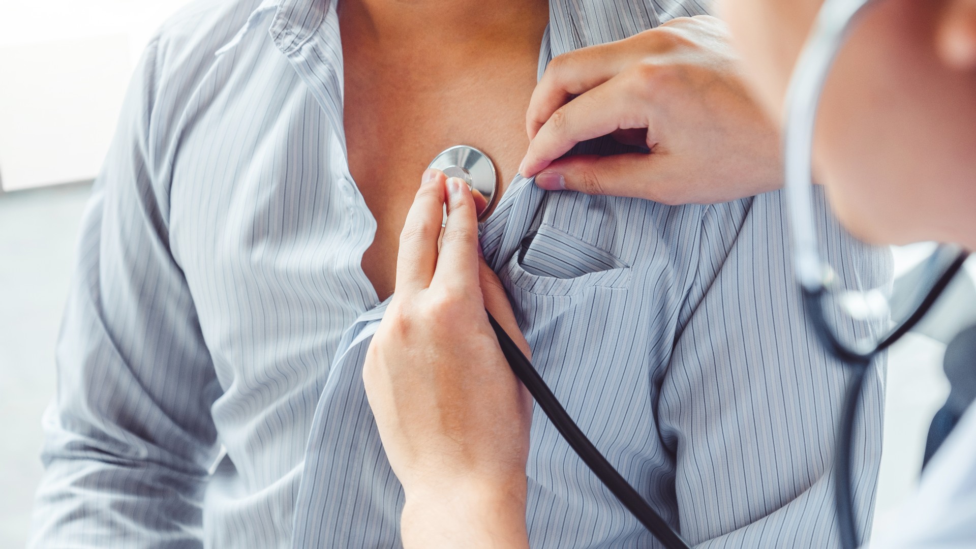 A doctor listening to a man's heart using a stethoscope