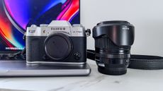 Fujifilm X-T50 camera body beside the XF16-50mmF2.8-4.8 R LM WR lens on a laptop keyboard