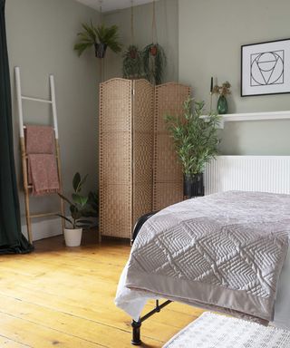 A bedroom with sage green wall paint decor and bamboo room divider