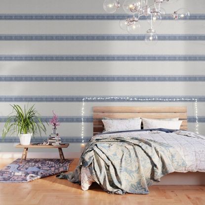 striped blue and white wallpaper in etherial sleeping space with wooden headboard 