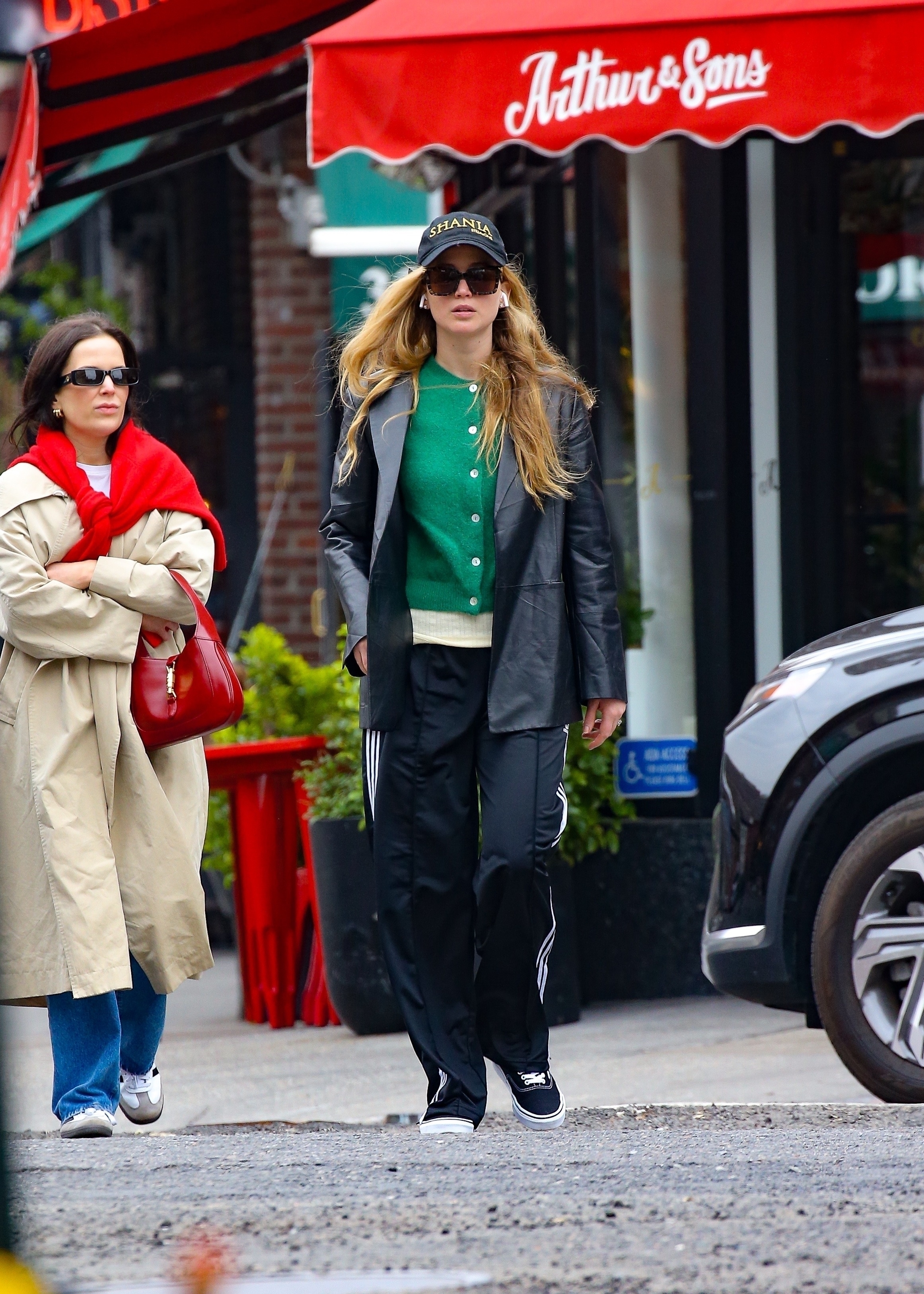 Jennifer Lawrence wears a green cardigan with black track pants and a leather blazer.