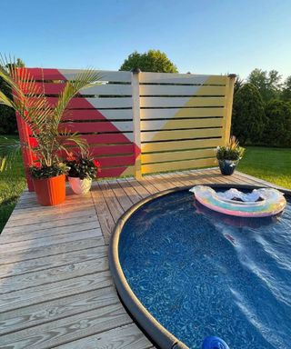 decking and stock tank pool with a brightly painted privacy fence