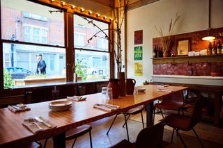 The rustic interiors of a bakery mix brutalism and mid-century modern-inspired details such as bricks, leathery seats, and linear silhouettes.