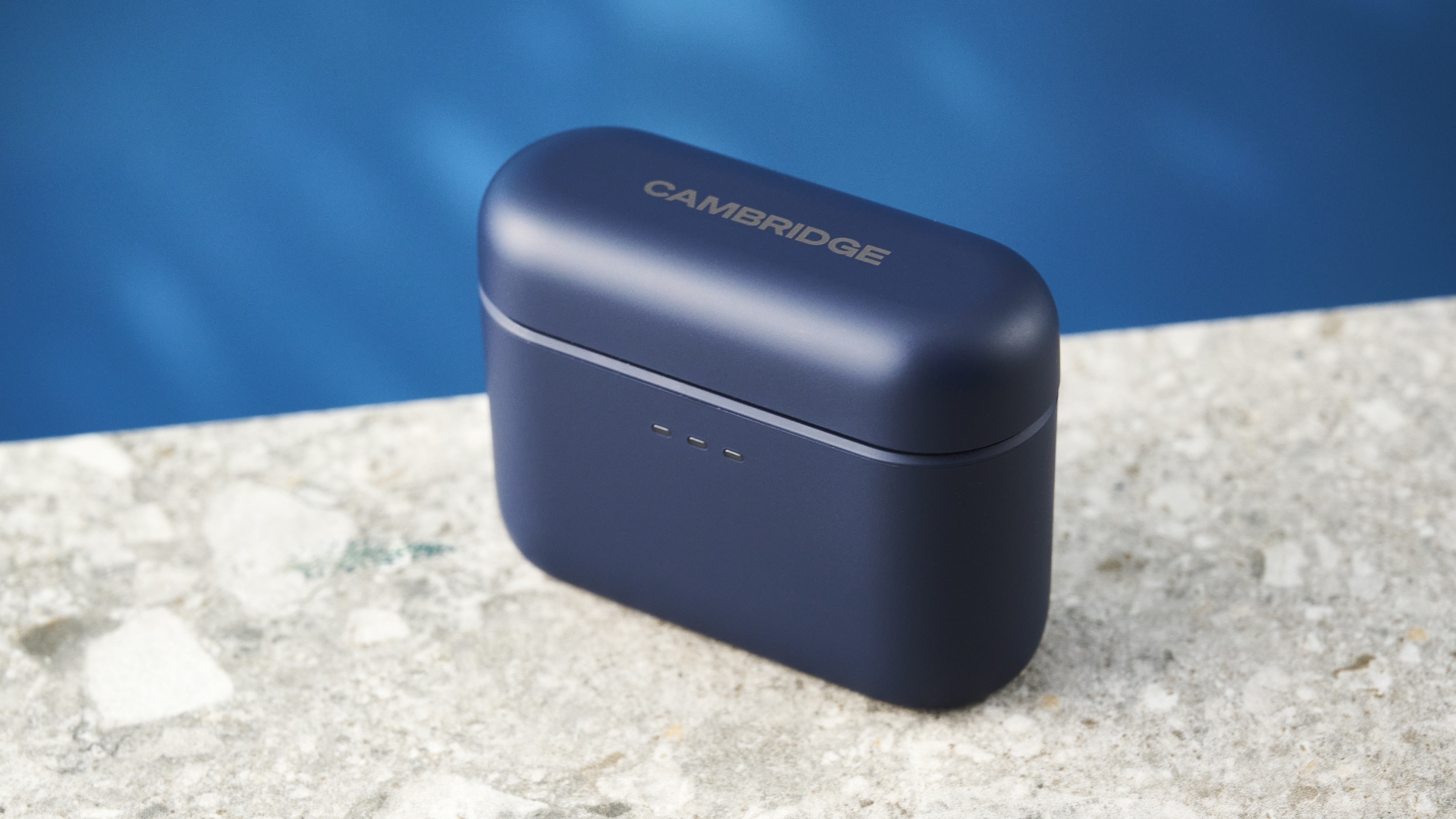the cambridge audio a100 se earbuds on a blue tom's guide background with a stone-coloured table underneath