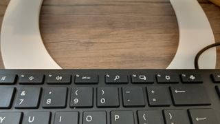 A white z-type Curve Flex laptop stand on a brown desk