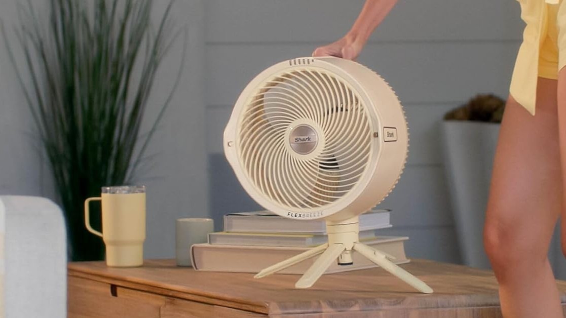 Woman placing Shark FlexBreeze Pro Mist fan in tabletop mode on wooden table
