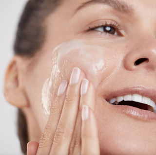 woman washing her face with a foaming glycolic acid cleanser