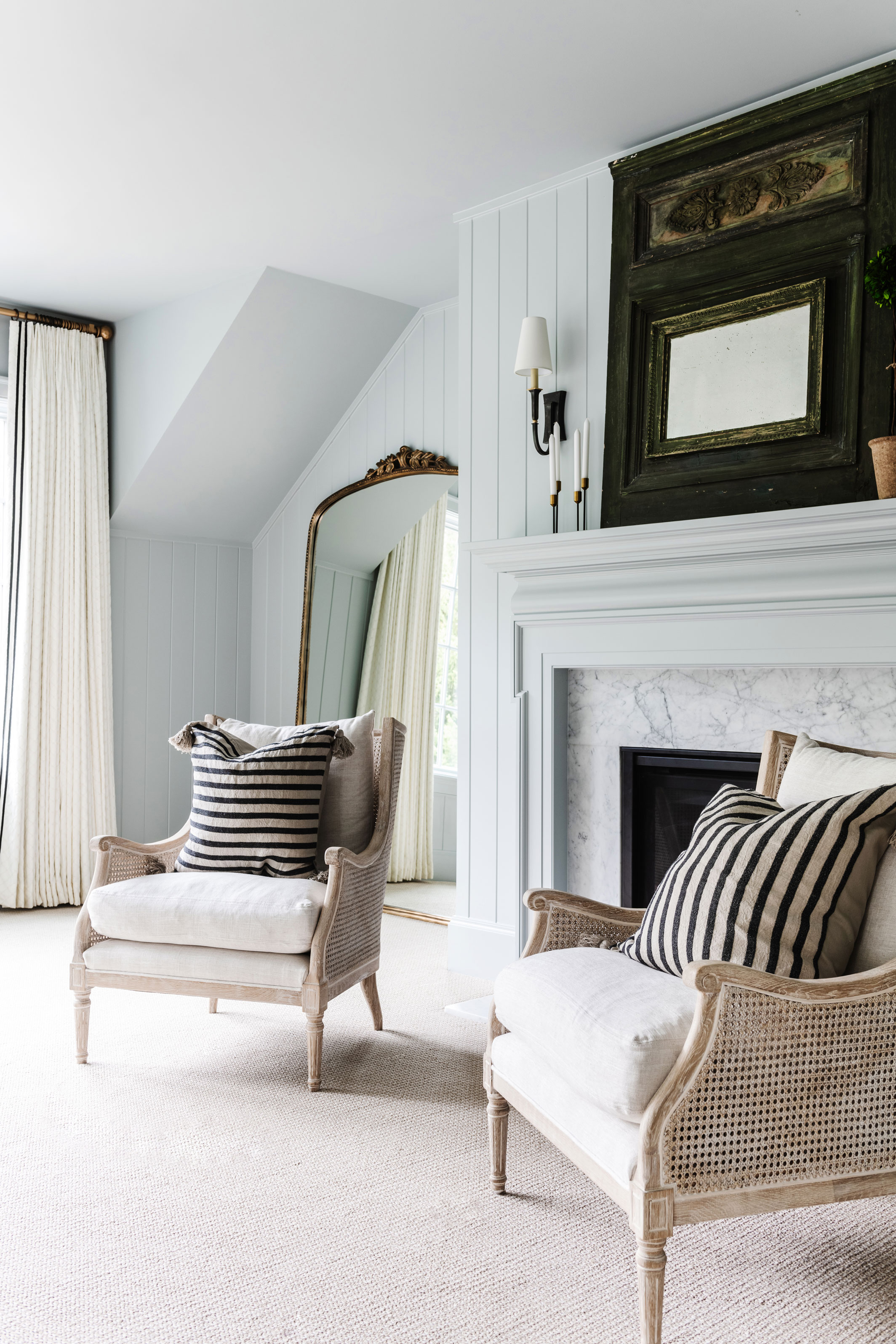 Bedroom looking towards fireplace with a floorstanding mirror behind a chair