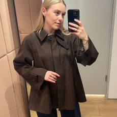 Woman wears deep burgundy cropped trench coat and blue jeans