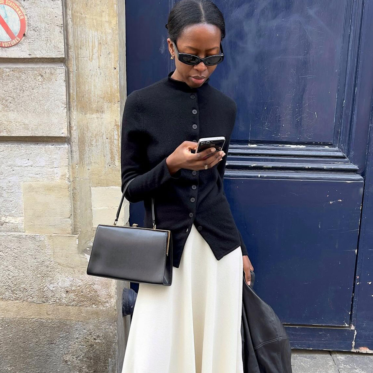 Woman in a black cardigan and white skirt