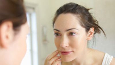 woman looking at her skin in the mirror