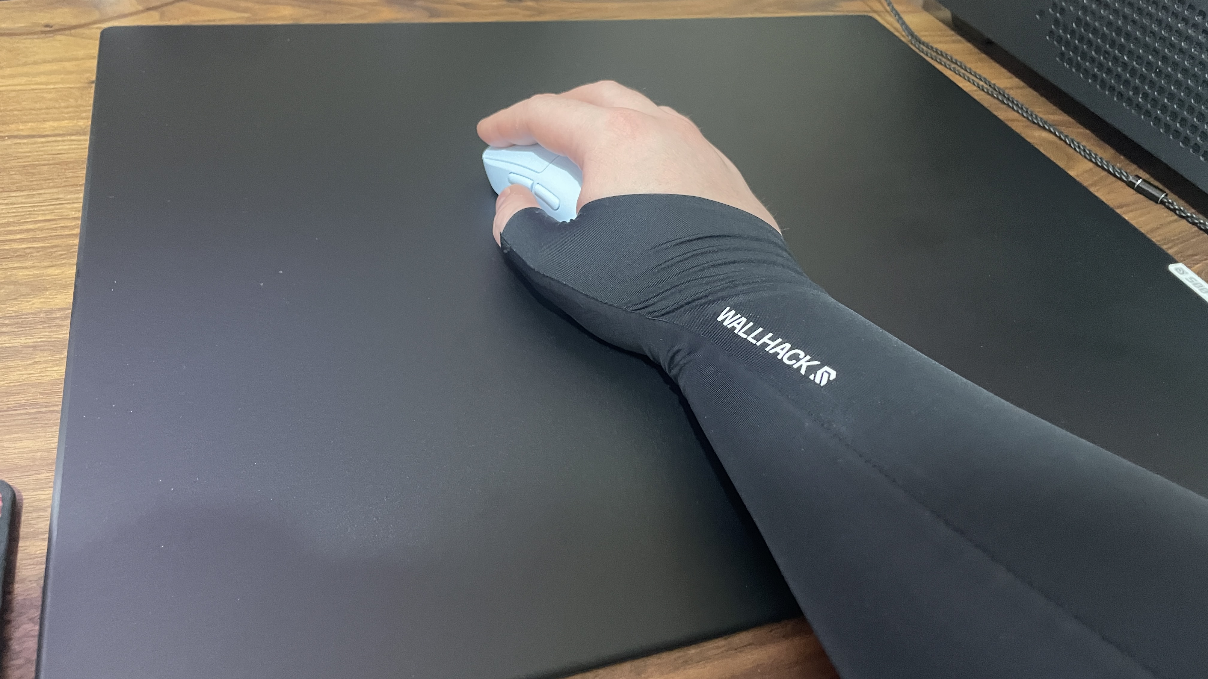 An arm holding a mouse, wearing a gamer sleeve.