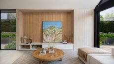 A minimalist living room with a low coffee table, a wood panelled focal wall and large windows