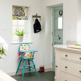 kitchen area with white wall and blue chair andd grey door