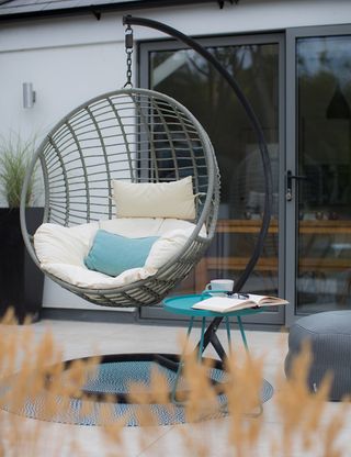 room with hanging chair tiled flooring and glass door