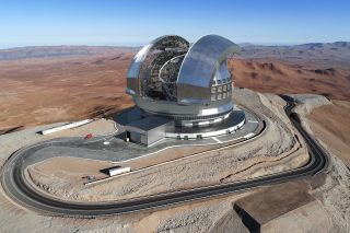 A rendering of what the ELT will look like. It seems to be a metal-colored, giant observatory in a desert-like region.