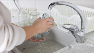 Person washing a jar under a running tap