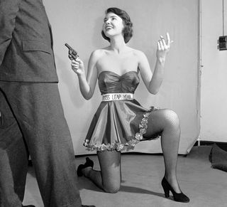 Miss Leap Year: Belinda Penelope seen here proposing to boyfriend holding a gun. February 1964 (Photo by WATFORD/Mirrorpix/Mirrorpix via Getty Images)