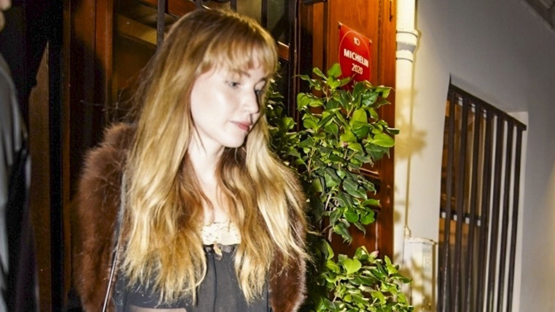 Jennifer Lawrence wearing a fur-trimmed coat, sheer top, baggy jeans, and leopard-print shoes in Paris