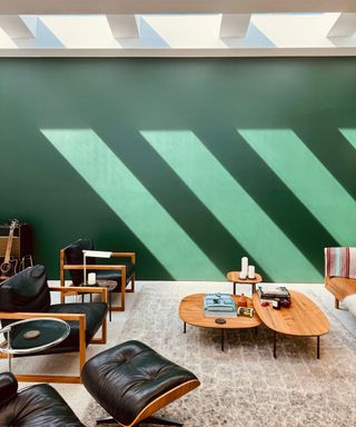 living room with green wall, skylight, and mid-century modern armchairs and coffee tables