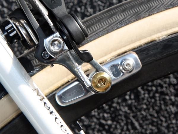 Shimano's Yumeya brake pad holders feature milled-out bodies and gold-anodized titanium hardware. Note the pad position in the brake arm slots, too, indicating the extra tire clearance.