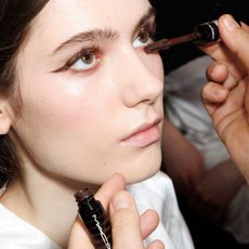 model backstage getting brown mascara applied
