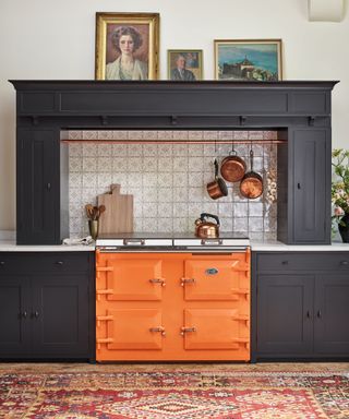 vintage styled kitchen with dark cabinets and an orange range cooker